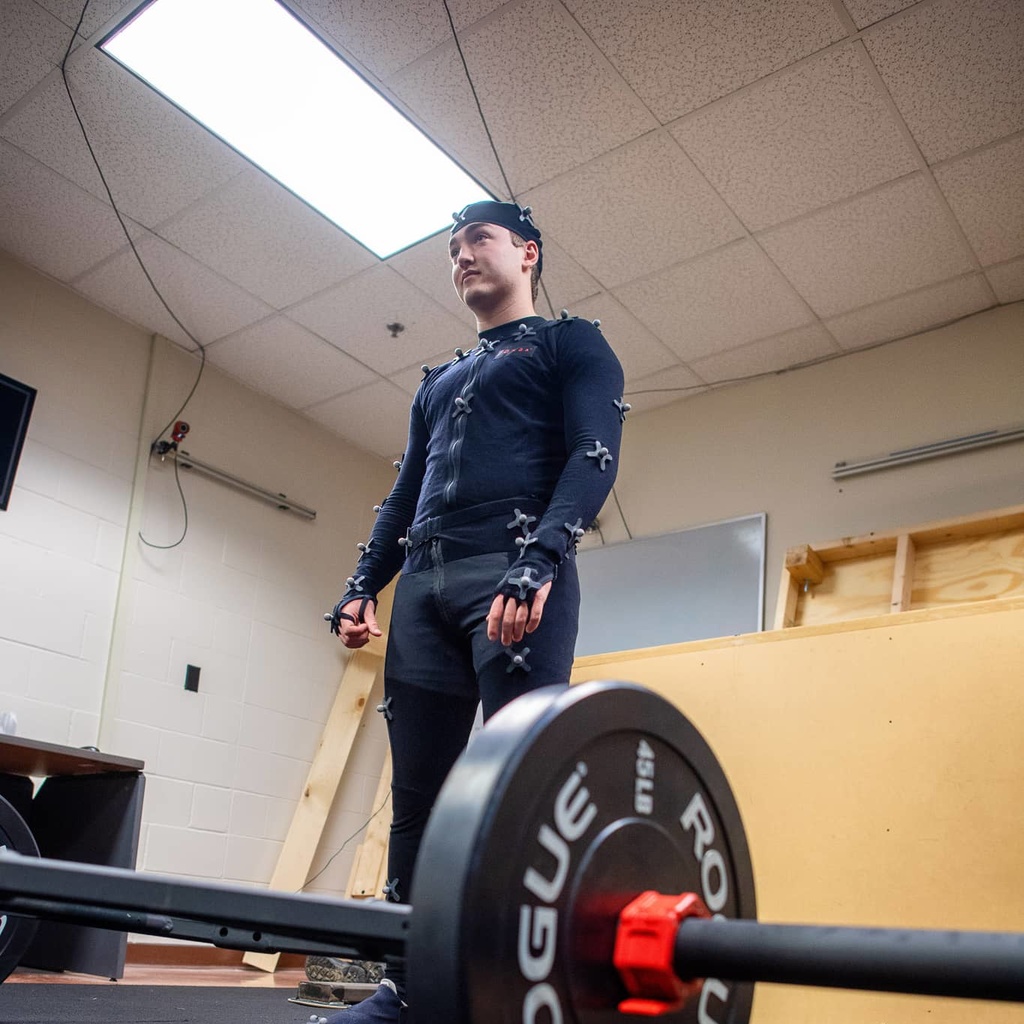 Person in a motion suit preparing to lift a barbell