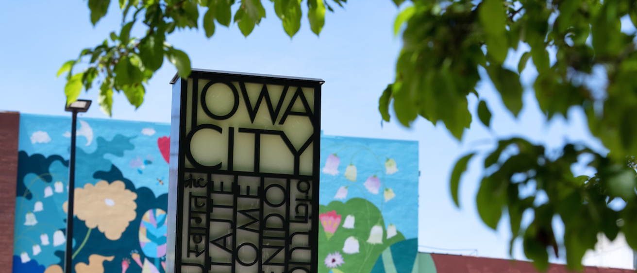 Iowa City sign with mural in background